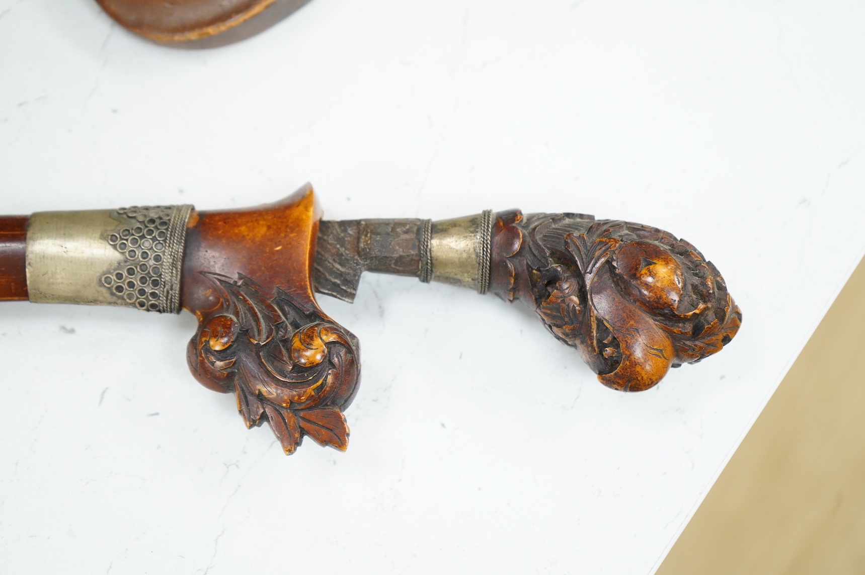 A Javanese dagger kris with straight pamor blade, wooden hilt carved as raksha, in its wooden sheath, together with a decorative dagger bade-bade, with etched blade
